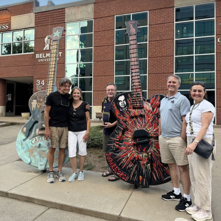 Tour group posing with painted guitar statues outside Belmont University on Music Row