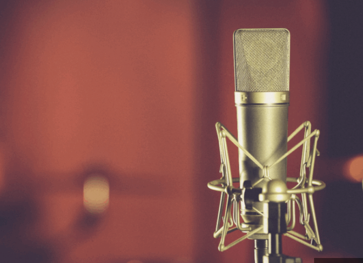 Vintage studio microphone glowing against a dark red backdrop